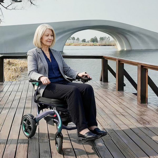 Woman sitting in a Wizemed C100 Carbon Fibre Folding Powerchair near a lake with an arched bridge in the background, in use.