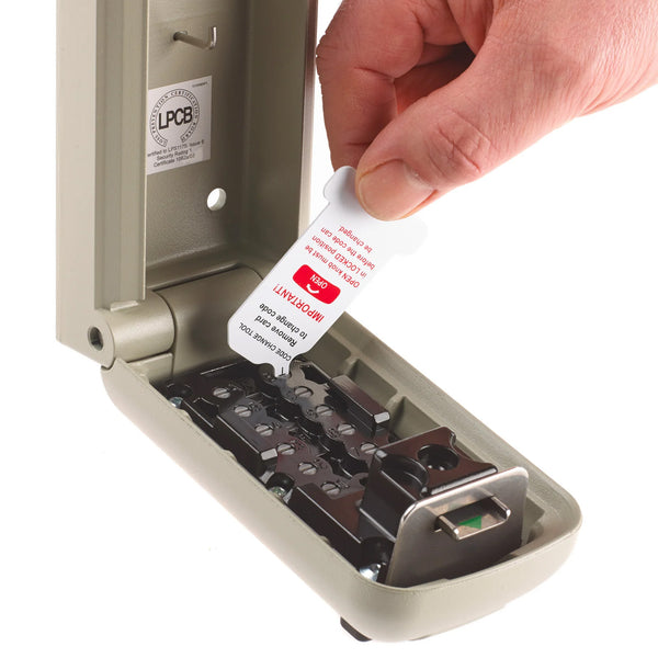 Hand placing a white and red card into an open Supra C500 Pro weather-resistant key safe, in use view.