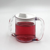 Homecraft Caring Mug with angled handles, white spill-proof lid and red liquid inside, front view.