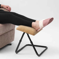 Feet in pink slippers on a Drive Comfy Adjustable Foot Stool with foam padding and black metal frame, next to beige sofa, in use.