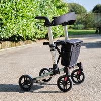 NRS Compact Easy Rollator four-wheeled walker with storage bag outdoors, side view.