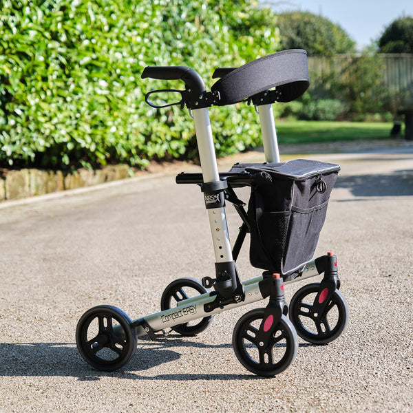 NRS Compact Easy Rollator four-wheeled walker with storage bag outdoors, side view.