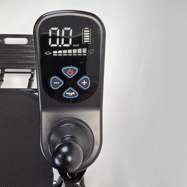 Dash Rehab Dash Carbon Max HD Power Chair digital panel showing 0.0 km/h with control buttons and joystick, close-up view.