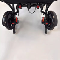Dash Rehab Dash Carbon Max HD Power Chair underside with two rear wheels and red locking mechanisms, close-up view.