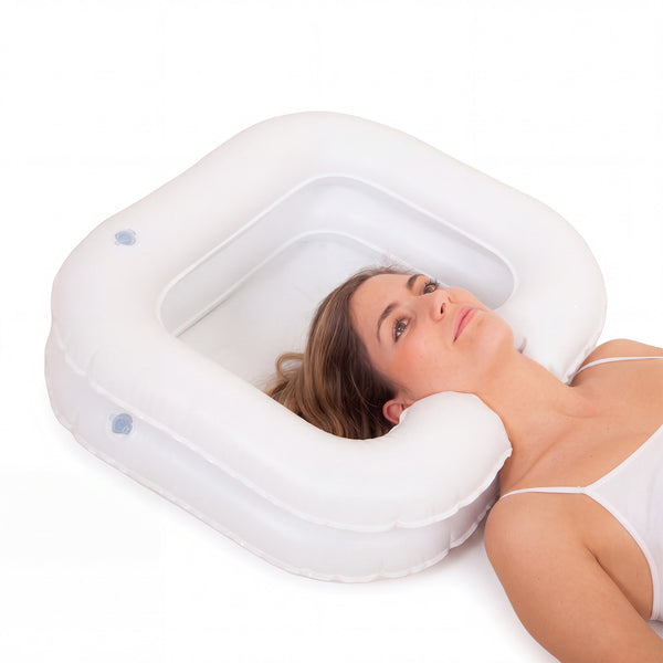 Woman lying with head in Able2 Deluxe Inflatable Shampoo Basin while having hair washed in bed, in use.