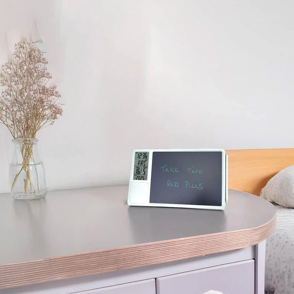 Lifemax Digital Memo Board and Day Date Clock displaying Take two red pills beside dried flowers in a vase, front view.