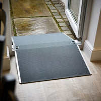 Enable Access Doorline Bridge Ramp with nonslip surface bridging indoor floor to outdoor patio, side view.