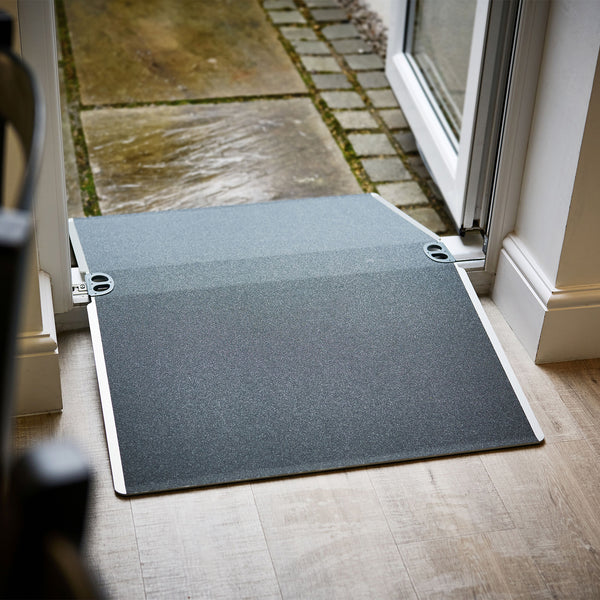 Enable Access Doorline Bridge Ramp with nonslip surface bridging indoor floor to outdoor patio, side view.