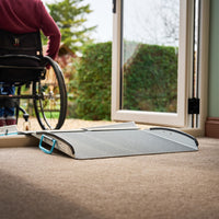 Wheelchair user approaching Enable Access Doorline-Multi Threshold Ramp at open uPVC door threshold, in use.