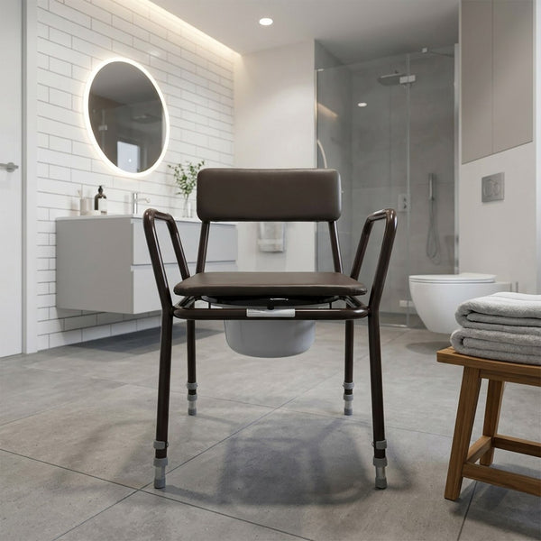 NRS Dovedale Extra Low Commode with armrests and removable bucket in a modern accessible bathroom, front view.