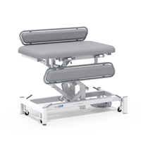 Medi-Plinth electric changing table with padded surface, side rails and caster wheels, NHS-approved, MRSA-resistant, side view.