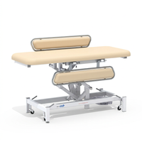 Medi-Plinth Electric Changing Table with adjustable height, metal frame, side rails and wheels, white background, side view.