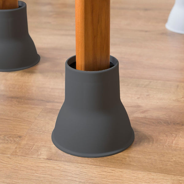 Wooden chair leg fitted with Elephant Feet raiser by Gordon Ellis, two more raised legs in background, close-up view.