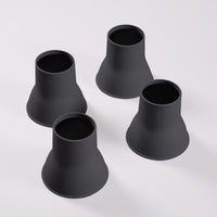 Four Elephant Feet bed and chair raisers by Gordon Ellis grouped together on a white surface, top-down view.