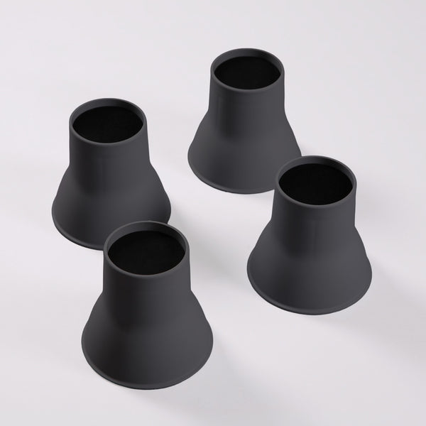 Four Elephant Feet bed and chair raisers by Gordon Ellis grouped together on a white surface, top-down view.