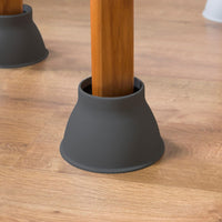Wooden table leg placed in a Gordon Ellis Elephant Feet Bed & Chair Raiser on light wood floor, close-up.