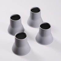 Four Gordon Ellis Elephant Feet Bed & Chair Raisers with black tops on a white surface, used to raise furniture, front view.