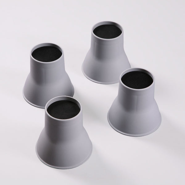 Four Gordon Ellis Elephant Feet Bed & Chair Raisers with black tops on a white surface, used to raise furniture, front view.