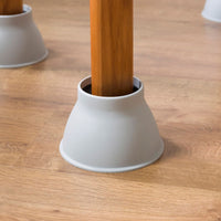 Table leg in a Gordon Ellis Elephant Feet furniture riser on a wooden floor, close-up.