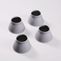 Four Gordon Ellis Elephant Feet bed and chair raisers with black tops, shown on a white surface, top view.