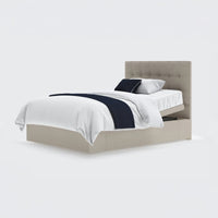 Opera Beds Emerald Motion Adjustable Divan Bed with tufted headboard, white bedding and blue accents on a white background, front view.