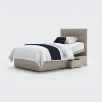 Adjustable divan bed with tufted headboard, white bedding, navy accents, two storage drawers, front view.