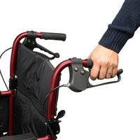 Hand holding brake of Days Escape Lite Wheelchair with black seat and armrests on white background, close-up.