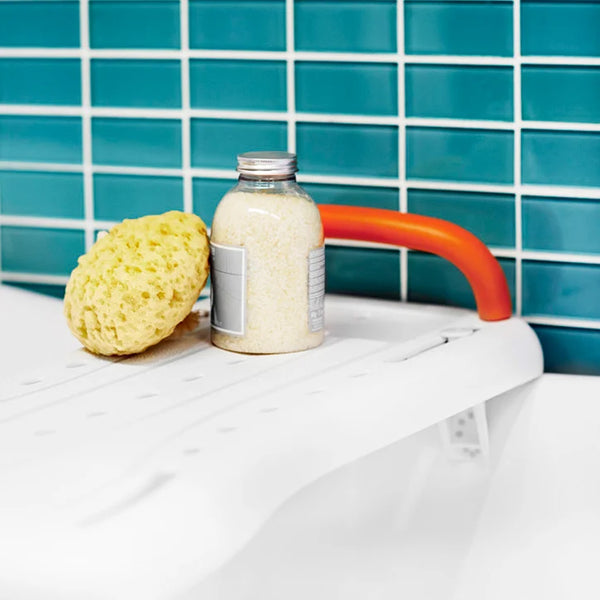 Etac Fresh Bath Board with Handle holding a sponge and bath salts, blue tiles in background, top angle.