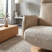Modern Motion Fitzroy Riser Recliner next to a wooden coffee table and rug in a softly lit room, front view.