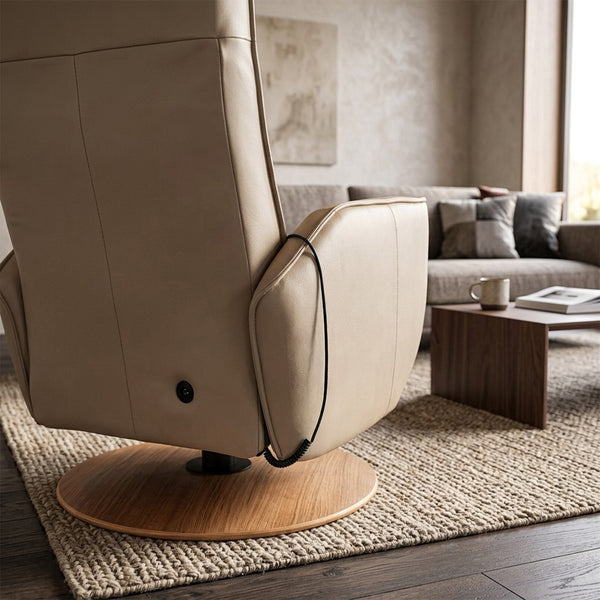 Modern Motion Fitzroy Riser Recliner Swivel Chair with control cord, on a rug next to a coffee table in a living room, front angle view.