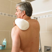 Older man cleaning his back with Homecraft Flannel Strap and Wash Mitt in a shower, beige tiles and toiletries in background, in use.
