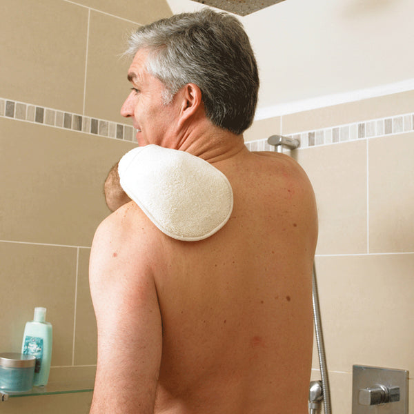 Older man cleaning his back with Homecraft Flannel Strap and Wash Mitt in a shower, beige tiles and toiletries in background, in use.