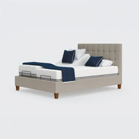 Opera Beds Flyte Adjustable Bed with split mattress, white bedding, blue pillows and blanket on wooden legs, front view.