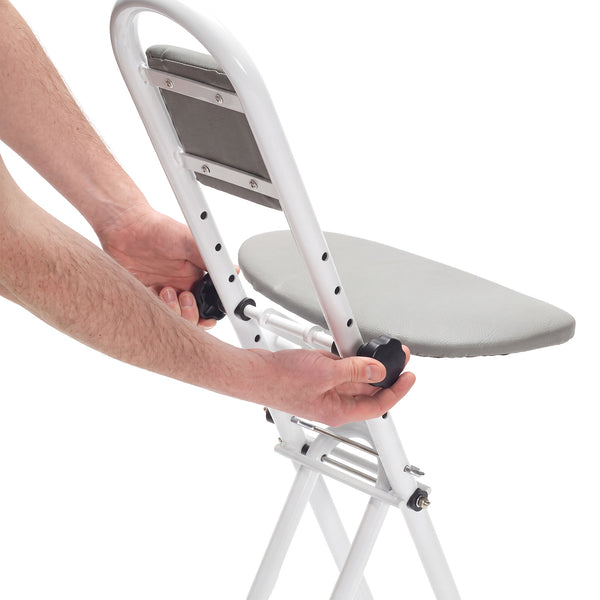 Drive Folding Perching Stool with padded seat, person adjusting knobs, in use, side view.