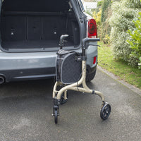 NRS Freestyle 3 Wheel Rollator with black bag behind open SUV boot on driveway next to greenery, rear angle.
