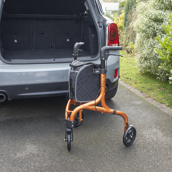 NRS Freestyle 3 Wheel Rollator with black bag positioned behind an open car boot on a driveway, rear view.
