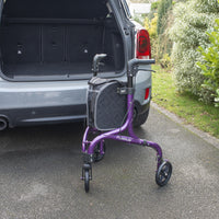 NRS Freestyle 3 Wheel Rollator with black bag next to open SUV boot on driveway near plants, side view.