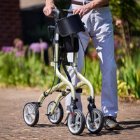 Person using NRS Freestyle 4 Wheel Rollator with bag outdoors among greenery, in use.