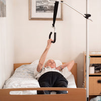 Elderly person in bed using GRIPO Bed Hoist, simple bedroom setting, in use angle.