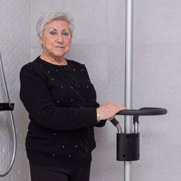 Woman using GRIPO Circular Grip 360° Support Ring for stability in a tiled bathroom, in use.
