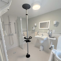 Accessible bathroom showing grab bars, shower seat, anti-slip sink, mirror, and circular support ring, front view.