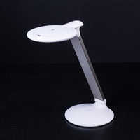 The Daylight Company Halo Go 2 Magnifying Lamp with circular base, rechargeable and adjustable arm on black background, front view.