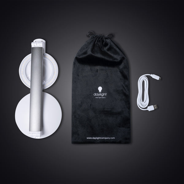 The Daylight Company Halo Go 2 Magnifying Lamp with pouch and USB cable on a dark surface, front view.