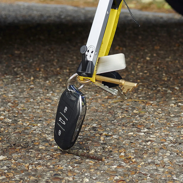 Helping Hand Classic Pro Folder holding keys above outdoor ground, in use.
