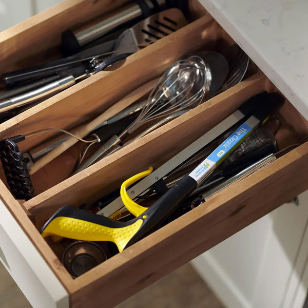 Kitchen drawer with wooden dividers organising utensils, whisks, measuring tape and Helping Hand Classic Pro Folder grabber tool, top view.