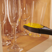 Handi-Grip Max grabber lifting a glass by wine glasses on a wooden shelf, in use.