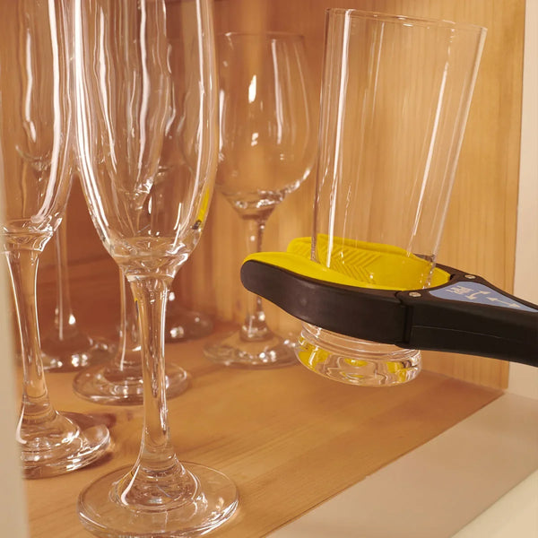 Handi-Grip Max grabber lifting a glass by wine glasses on a wooden shelf, in use.