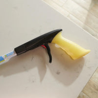 Helping Hand Handi-Grip Max grabber tool with trigger handle placed on marble surface, top view.