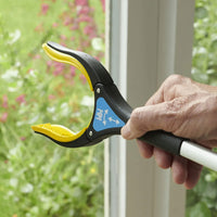 Helping Hand Handi-Grip Pro being held by a hand near a window with garden visible outside, in use view.