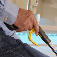 Person using Helping Hand Handi-Grip Pro reaching aid to pick up an item while seated, close-up.